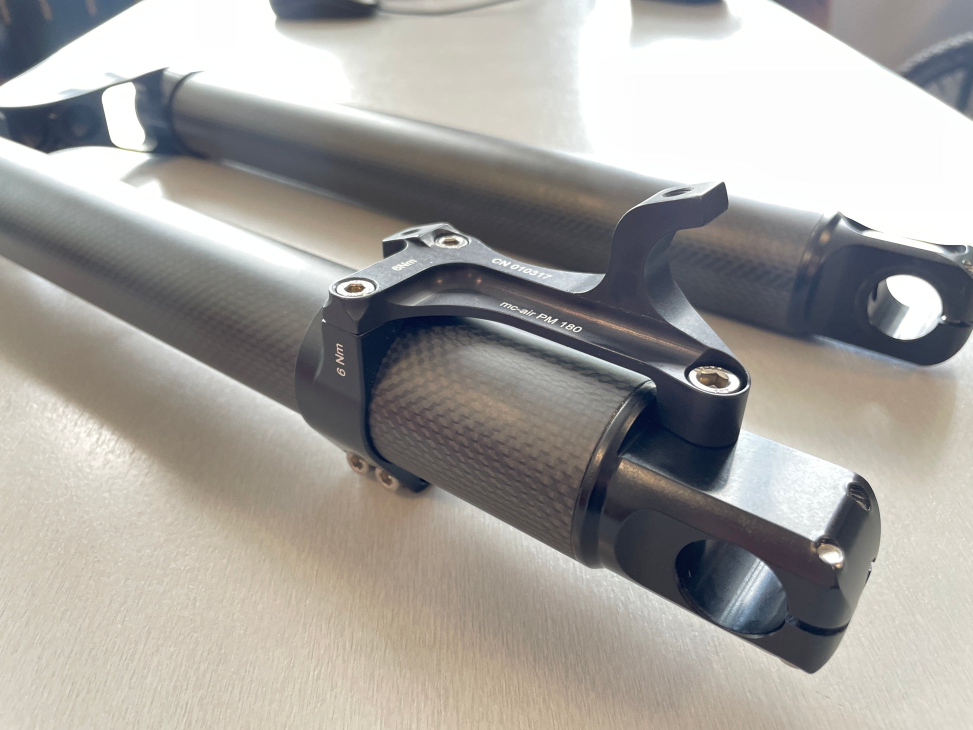 On a table lies the lower part of a Votec fork made of carbon. The two fork legs and the brake mount are clearly visible.