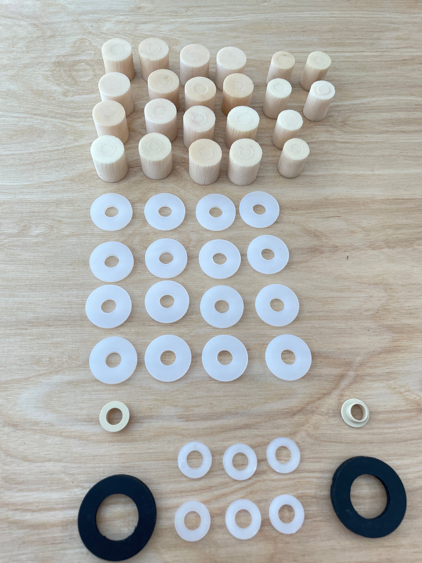 A complete set of elastomers, spacers, and end stops for a Votec GS4 suspension fork, suitable for a rider weight of 60 kg, neatly arranged on a wooden surface. The elastomers and washers are sorted by size and function.