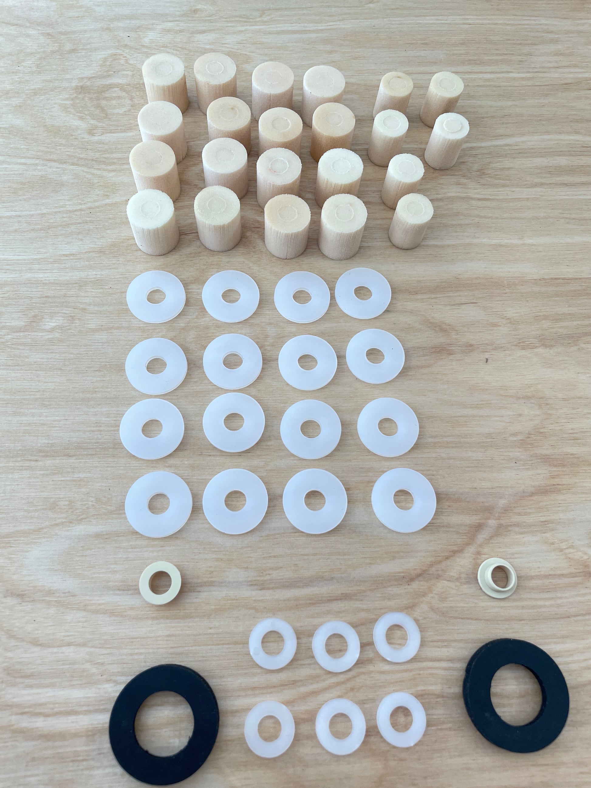 A complete set of elastomers, spacers, and end stops for a Votec GS4 suspension fork, suitable for a rider weight of 60 kg, neatly arranged on a wooden surface. The elastomers and washers are sorted by size and function.