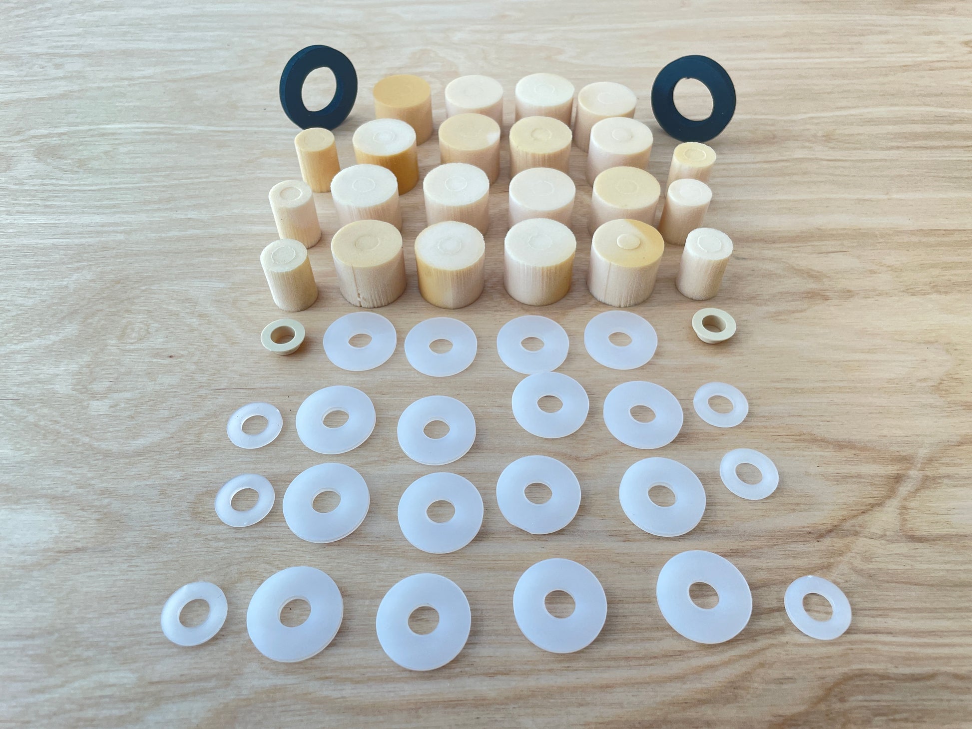 A complete set of elastomers, spacers, and end stops for a Votec GS4 suspension fork, suitable for a rider weight of 80 kg, neatly arranged on a wooden surface. The elastomers and washers are sorted by size and function.